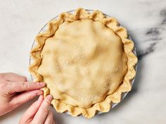 a pie crust is being held up by two hands