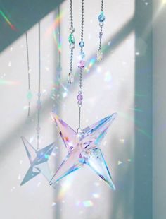 an origami star hanging from a chain in front of a window with the sun shining through it