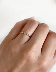 a woman's hand with a gold ring on her left hand and a white background