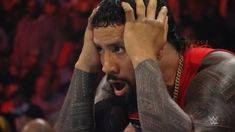 a man with his hands on his head in the middle of a wrestling match,