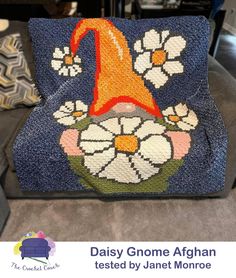 a blue chair with flowers on it and the words daisy gnome afghan tested by janet monroe