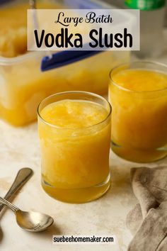 two glasses filled with vodka slush on top of a counter next to spoons