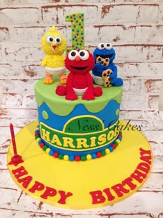 a birthday cake with the number one on it and sesame street characters sitting on top