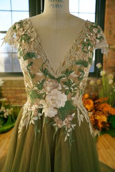 a dress with flowers on it is displayed in front of a brick wall and window