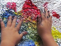 two hands touching each other with their fingers on tin foil and colored crayons