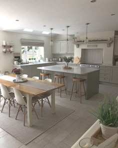 a large open kitchen and dining room area with an island table in the middle, surrounded by stools