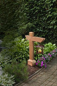 a wooden cross sitting in the middle of a garden