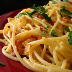 a red plate topped with pasta and parsley