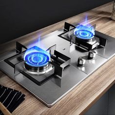 two burners on the top of a stainless steel gas stove with blue flames