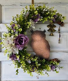 a wreath with an owl and flowers hanging on the front door to hang it's decorations