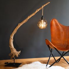 a chair and lamp in a room next to a tree branch with a light bulb on it