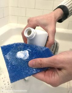 someone is cleaning the bathroom sink with a blue sponge and a white sprayer on it