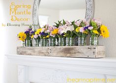 flowers are arranged in glass vases on a mantel with a mirror above it