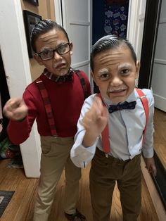 two young boys standing next to each other in front of a door wearing suspenders and bow ties