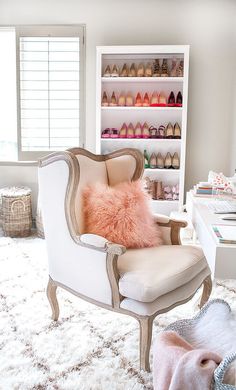 a white chair sitting on top of a rug next to a shoe rack filled with shoes