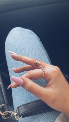 a woman's hand with pink nail polish and ring on her finger, sitting in the back seat of a car