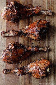 three pieces of meat sitting on top of a wooden cutting board next to each other