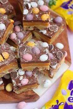 a wooden cutting board topped with lots of chocolate and candy bar pieces on top of each other