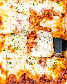 a close up of a pizza in a pan with cheese and sauce on it, being cut by a spatula