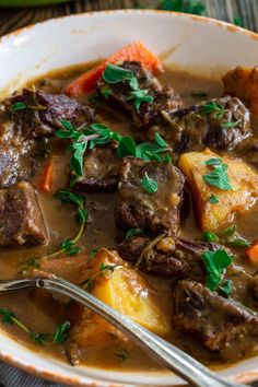 a close up of a bowl of food with meat and vegetables in it on a table