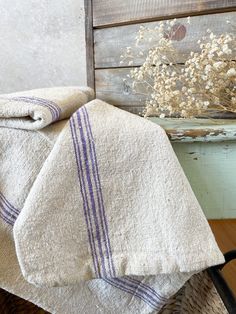 two towels are folded next to a basket with dried flowers in it on a table