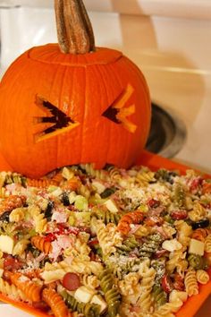 a pumpkin sitting on top of a bowl filled with pasta and vegtables