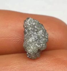 a close up of a person's hand holding a piece of silver colored rock