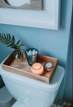 a white toilet sitting next to a wooden tray filled with flowers and candles on top of it