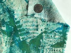 a coin is sitting on top of a green and blue rug with fringes around it