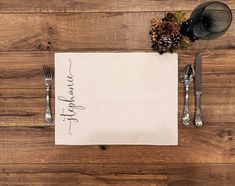 a place setting on a wooden table with silverware, napkin and utensils