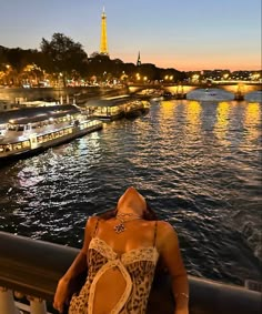 a woman in a leopard print bathing suit sitting on a railing overlooking the water at night