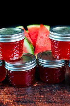 several jars filled with jam next to slices of watermelon