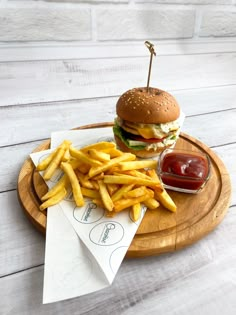 a hamburger and french fries on a wooden plate