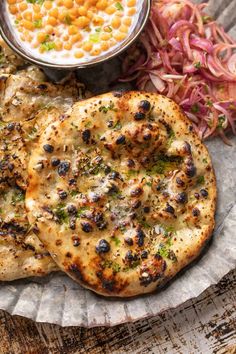 two pieces of pizza sitting on top of a paper plate next to coleslaw