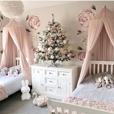 a baby's room decorated in pink and white with flowers on the wall, crib bedding, two twin beds, and a christmas tree