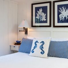 two framed pictures hang on the wall above a bed with blue and white pillows in a bedroom