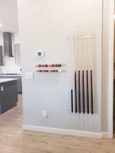 a wall mounted rack with pool balls and cues on it in a kitchen area