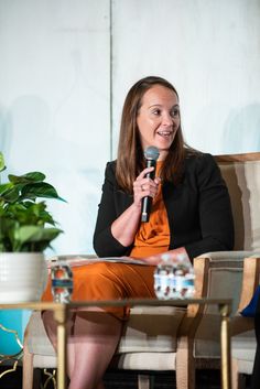 a woman sitting in a chair holding a microphone