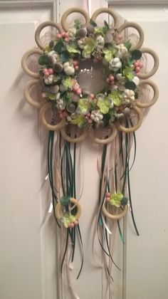 a wreath hanging on the front door with flowers and ribbons attached to it's sides