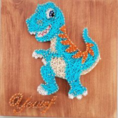 a string art dinosaur on a wooden board with the word dino spelled out in orange and blue