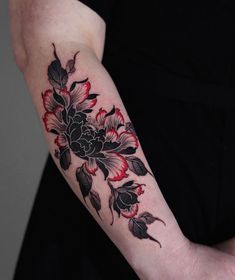 a woman's arm with flowers and leaves tattooed on the left side of her arm