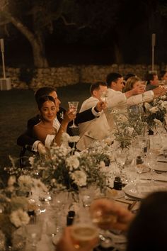 a group of people sitting at a table with wine glasses in front of their faces