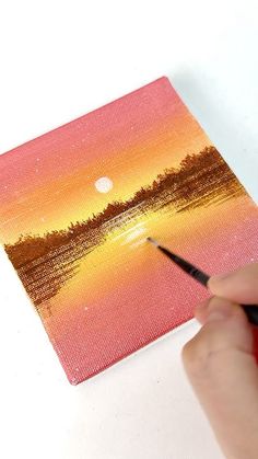 someone is painting a sunset scene with acrylic paint on canvases and using a brush