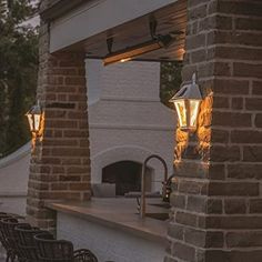 an outdoor bar with chairs and lights on the outside wall, next to a brick oven