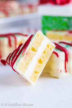 two pieces of cake with white frosting and red icing on them sitting next to each other