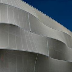 the exterior of an architectural building with wavy lines on it's side and blue sky in the background