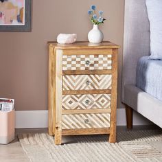 a wooden dresser sitting next to a bed with a vase and flowers on top of it