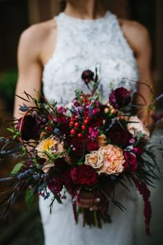 a woman holding a bouquet of flowers in her hands and wearing a white dress with red accents