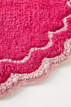 a pink and white area rug on a white surface with an intricate design in the middle