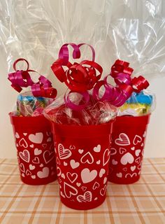 three red plastic buckets filled with candy and candies on top of a table